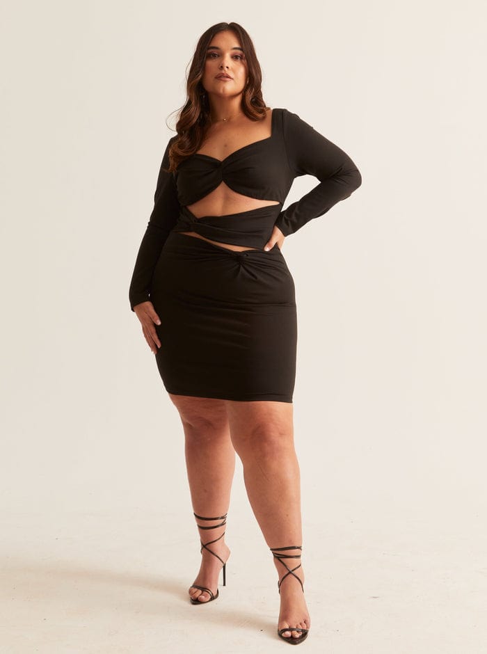 A woman wearing a black bodycon mini dress with long sleeves