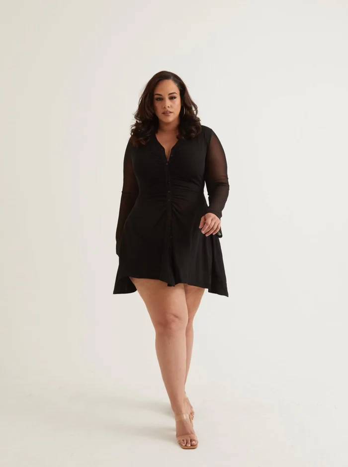 A woman wearing a black mini dress with bell sleeves