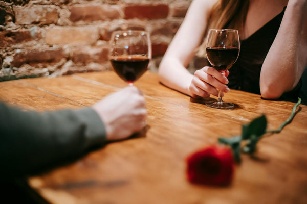 a man and woman having dinner with wine and a rose on the table