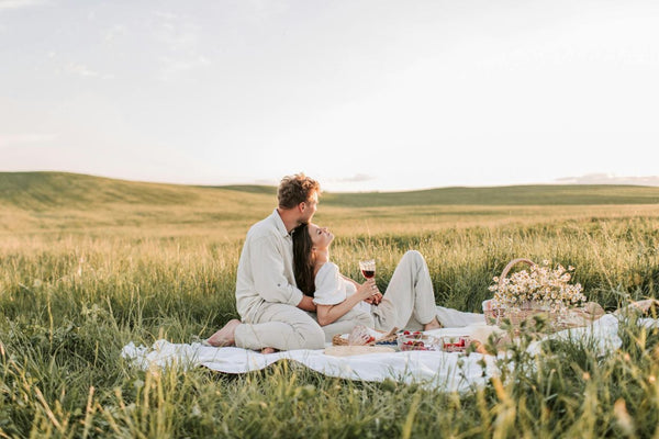 A man and woman enjoying a picnic date in a field