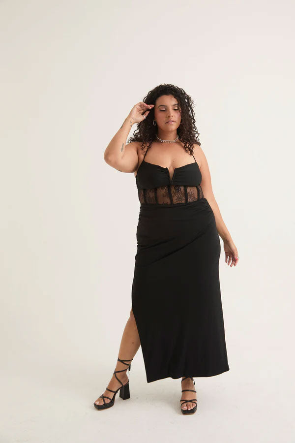 Woman wearing a black date night midi dress with mesh corset detailing