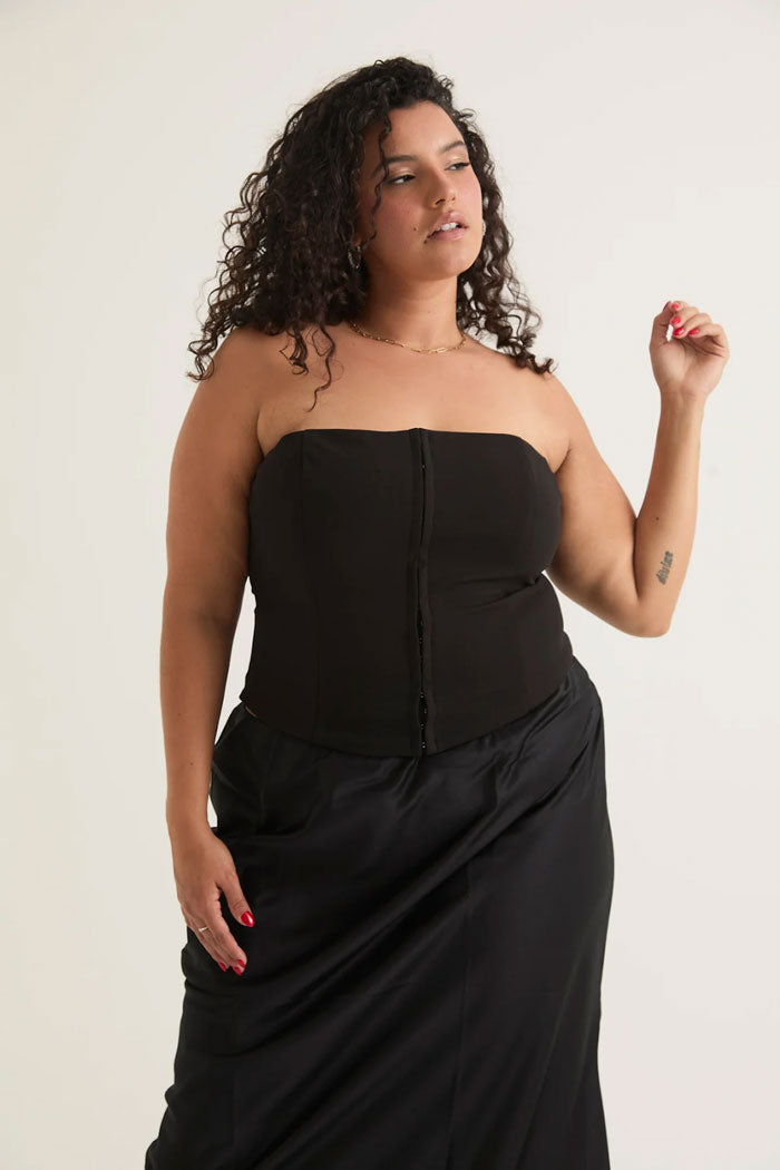 Woman in a black strapless corset top and a black maxi skirt