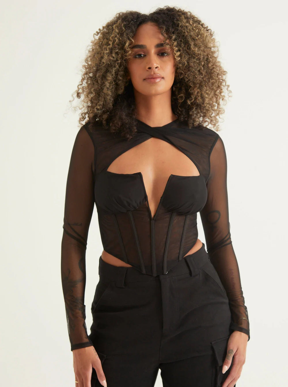 Model wearing a women's cut-out top with black pants